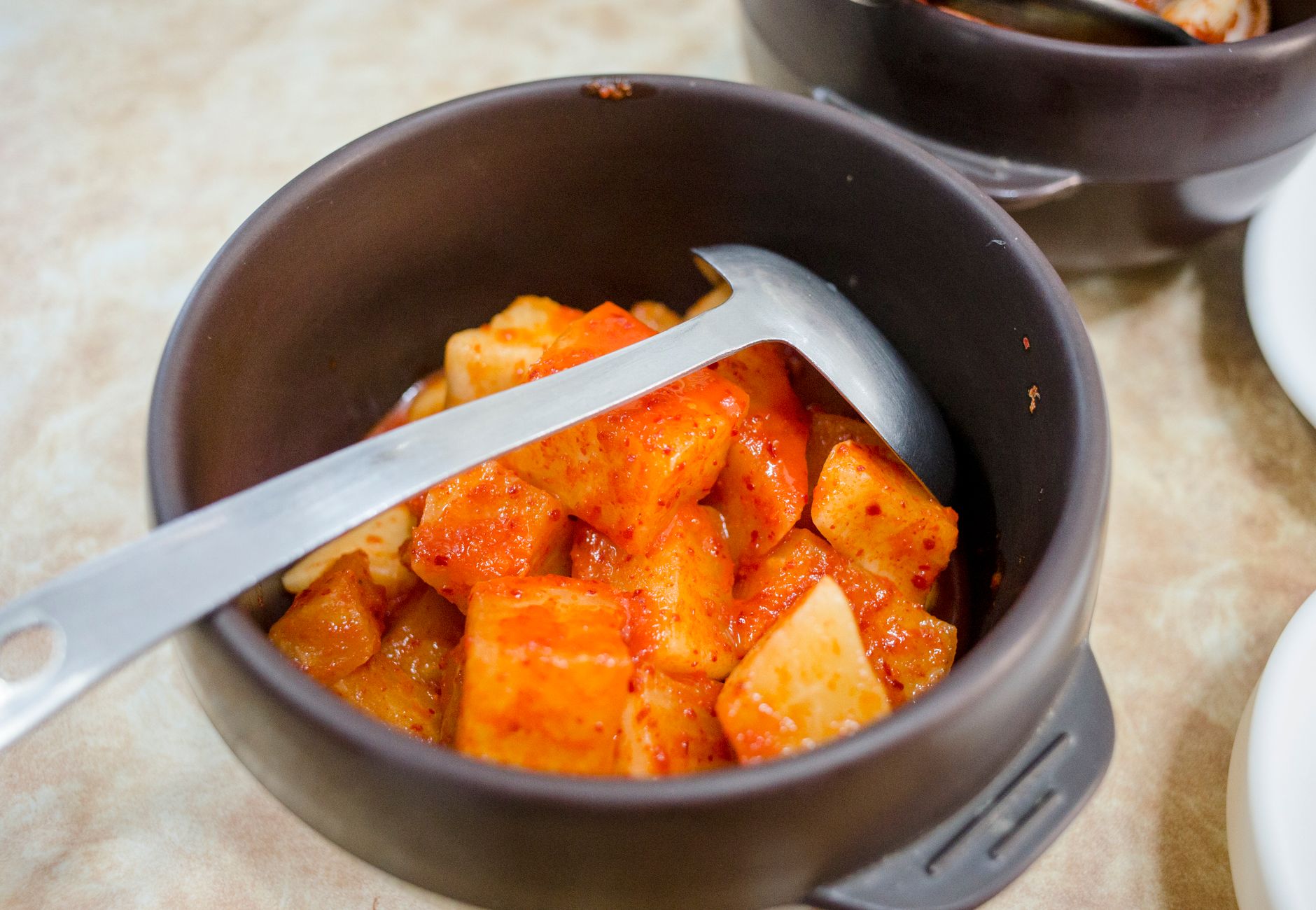 Close-up of homemade spicy kimchi in a ceramic bowl, showcasing vibrant flavors.